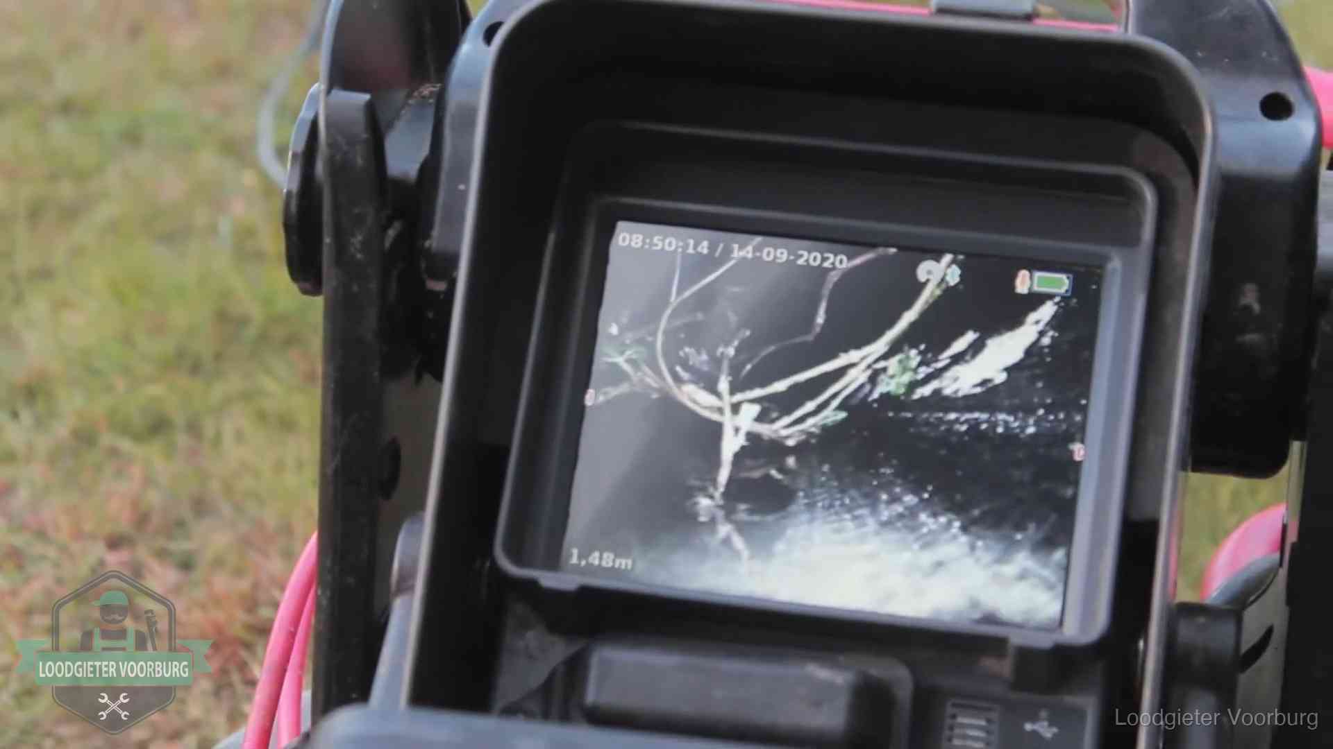 Monitor van een rioolcamera toont wortelingroei in de rioolbuis bij een woning in Voorburg