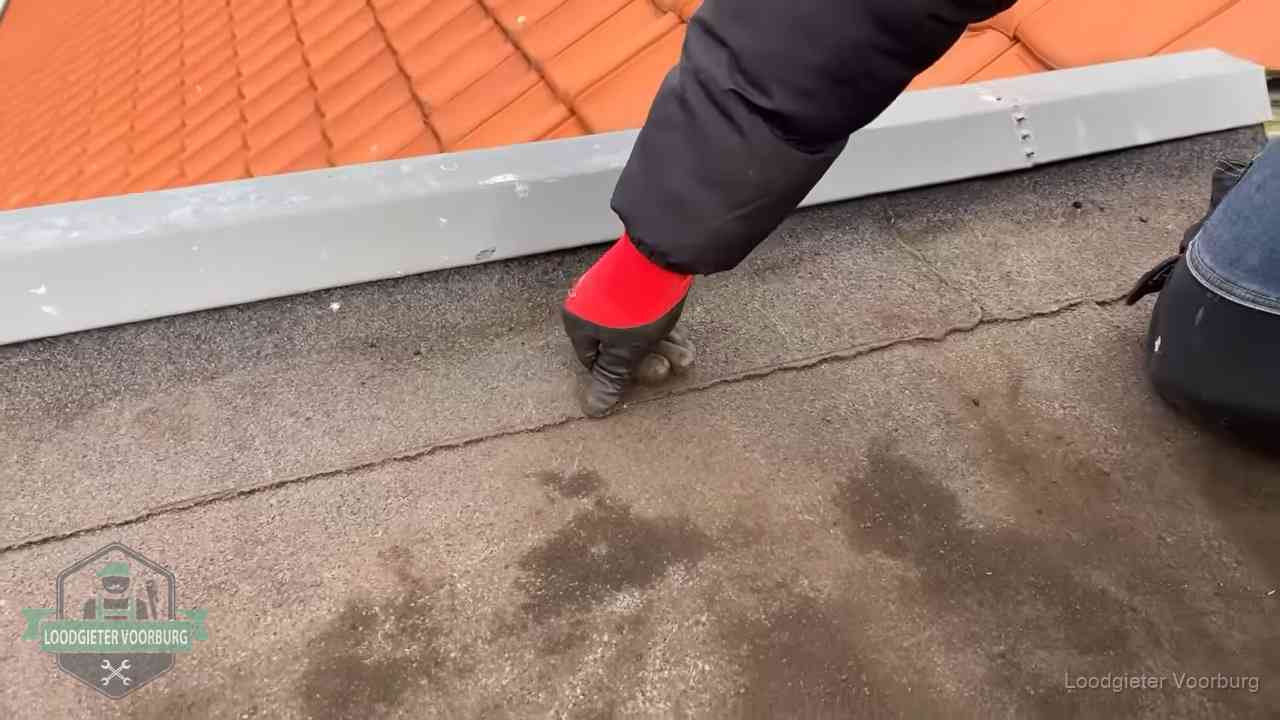 Lekkage bij de naad van een plat dak in Voorburg Vakman wijst een naad met vochtplekken aan op een bitumen plat dak in Voorburg