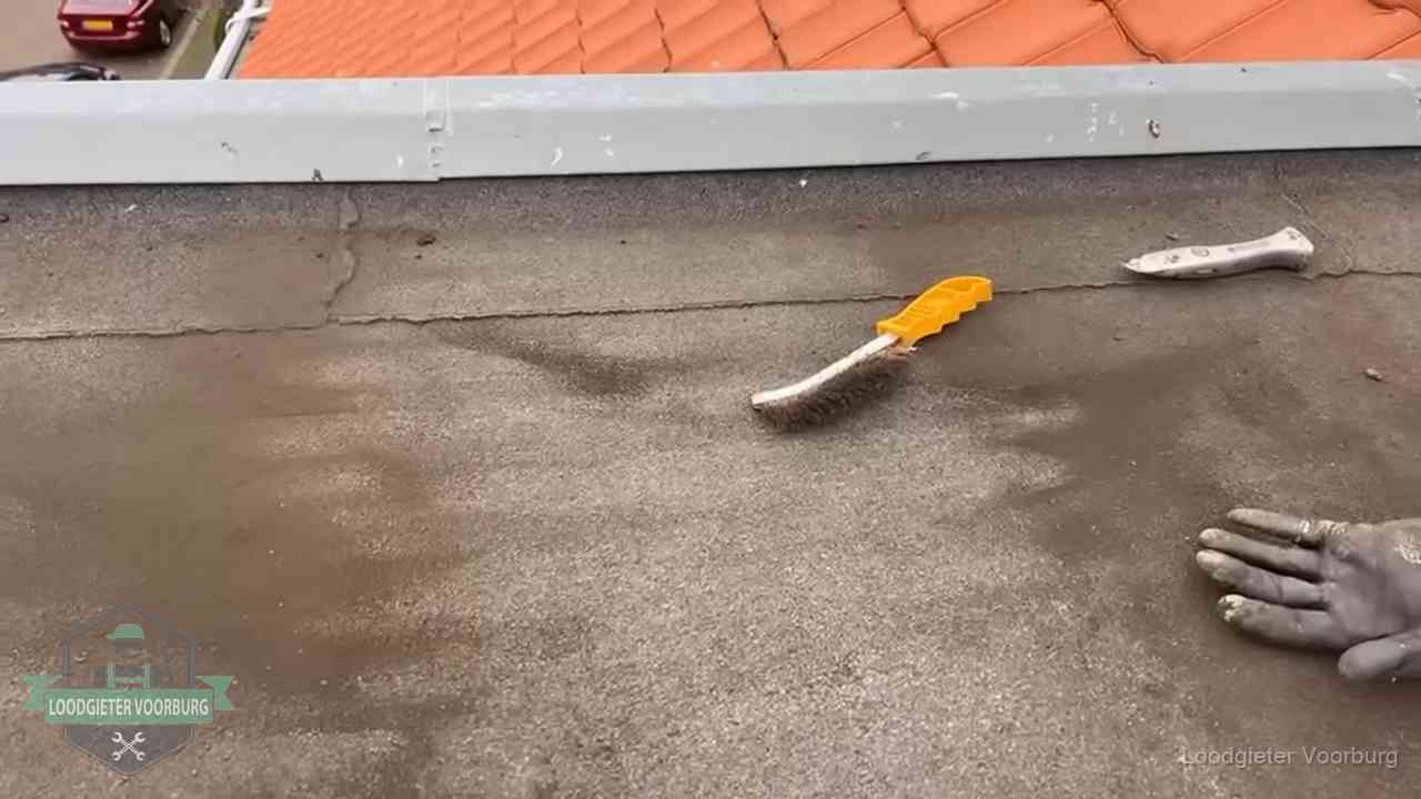 Kosten van daklekkage-reparatie in Voorburg Dakdekker bereidt een bitumen plat dak voor op reparatie bij de daktrim in Voorburg