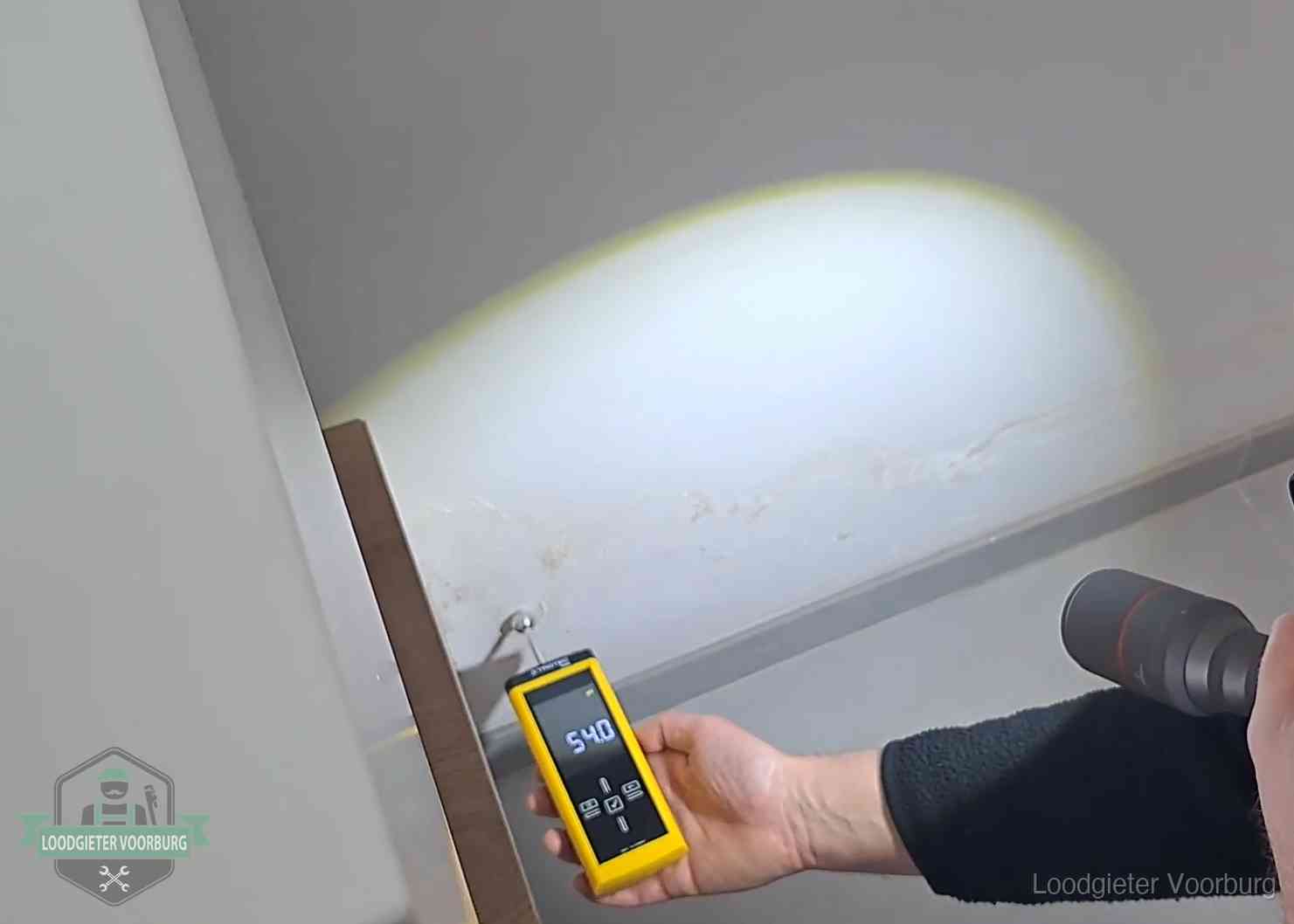 Vochtmeter tegen een natte wand met lekkagesporen in Voorburg