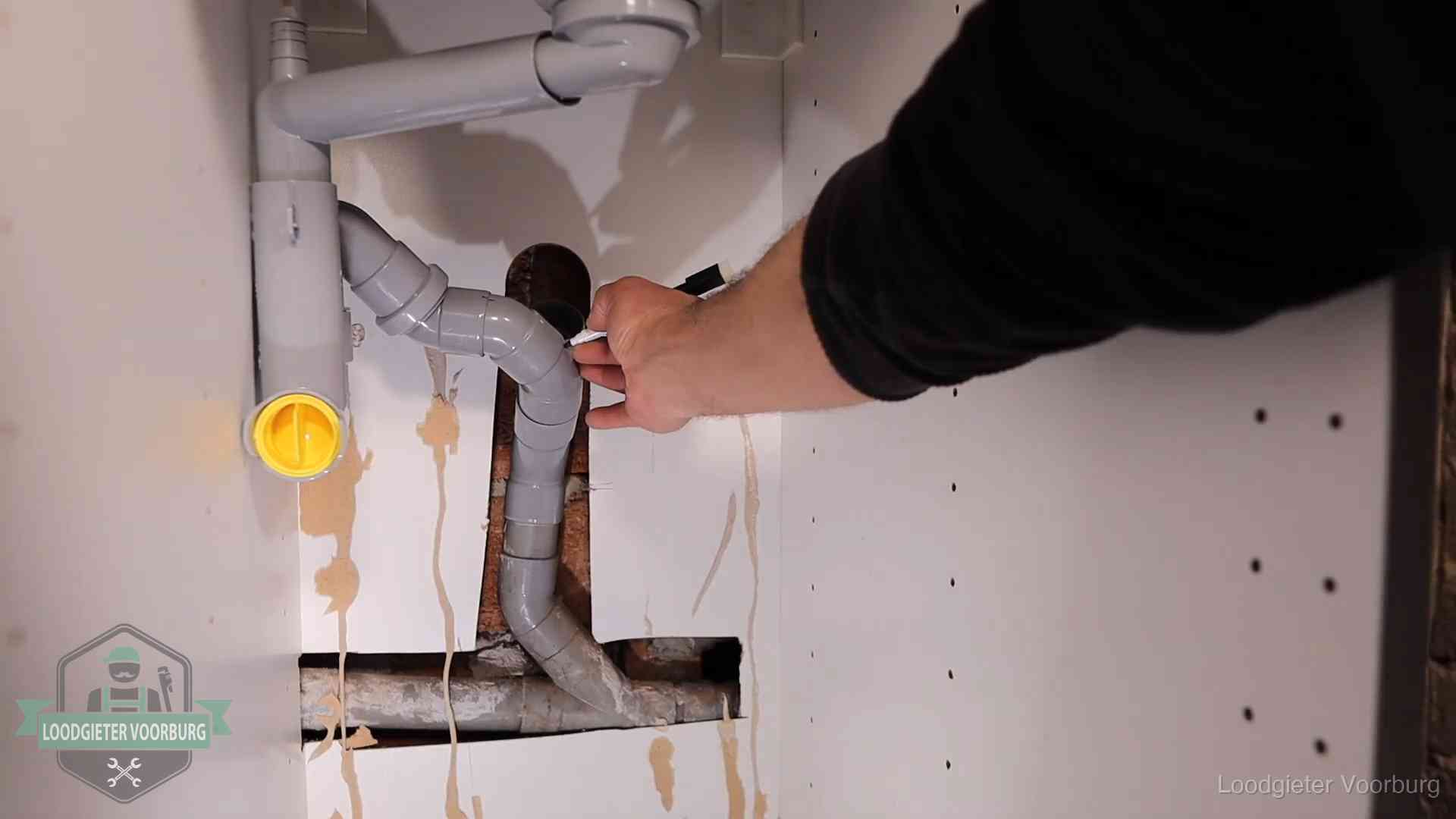 Loodgieter voor verhuurders en bedrijven in Voorburg Loodgieter markeert een pvc-afvoerbuis onder een gootsteen in Voorburg