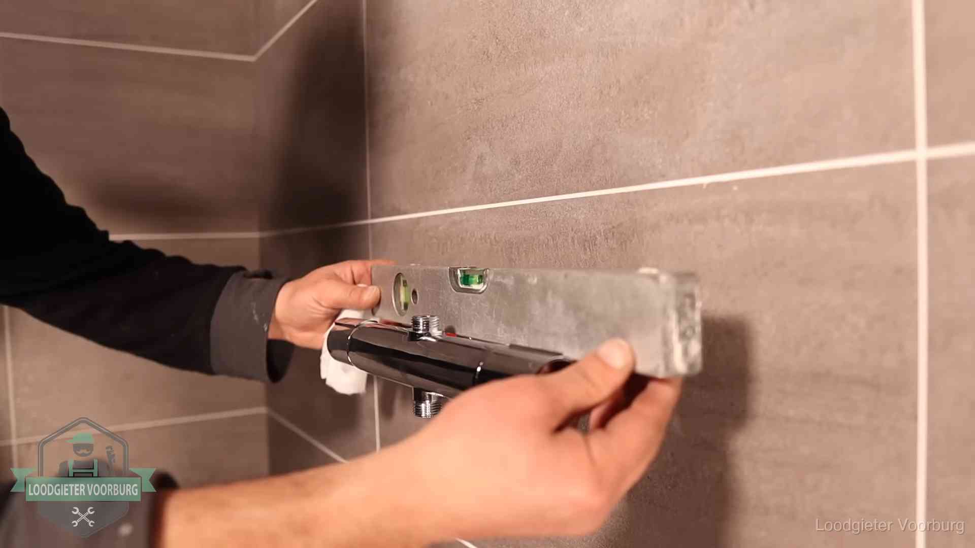 Loodgietersbedrijf voor sanitair in Voorburg Loodgieter lijnt een douchekraan uit met een waterpas in een woning in Voorburg