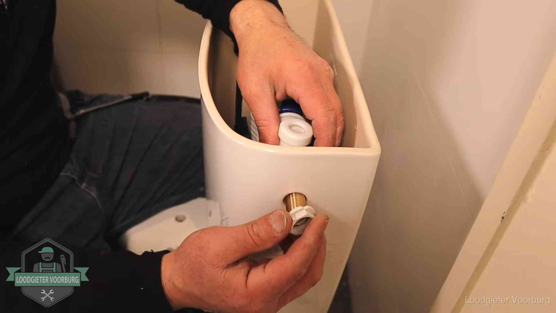 Loodgieter monteert de vlotterkraan van een stortbak bij een toilet in Voorburg