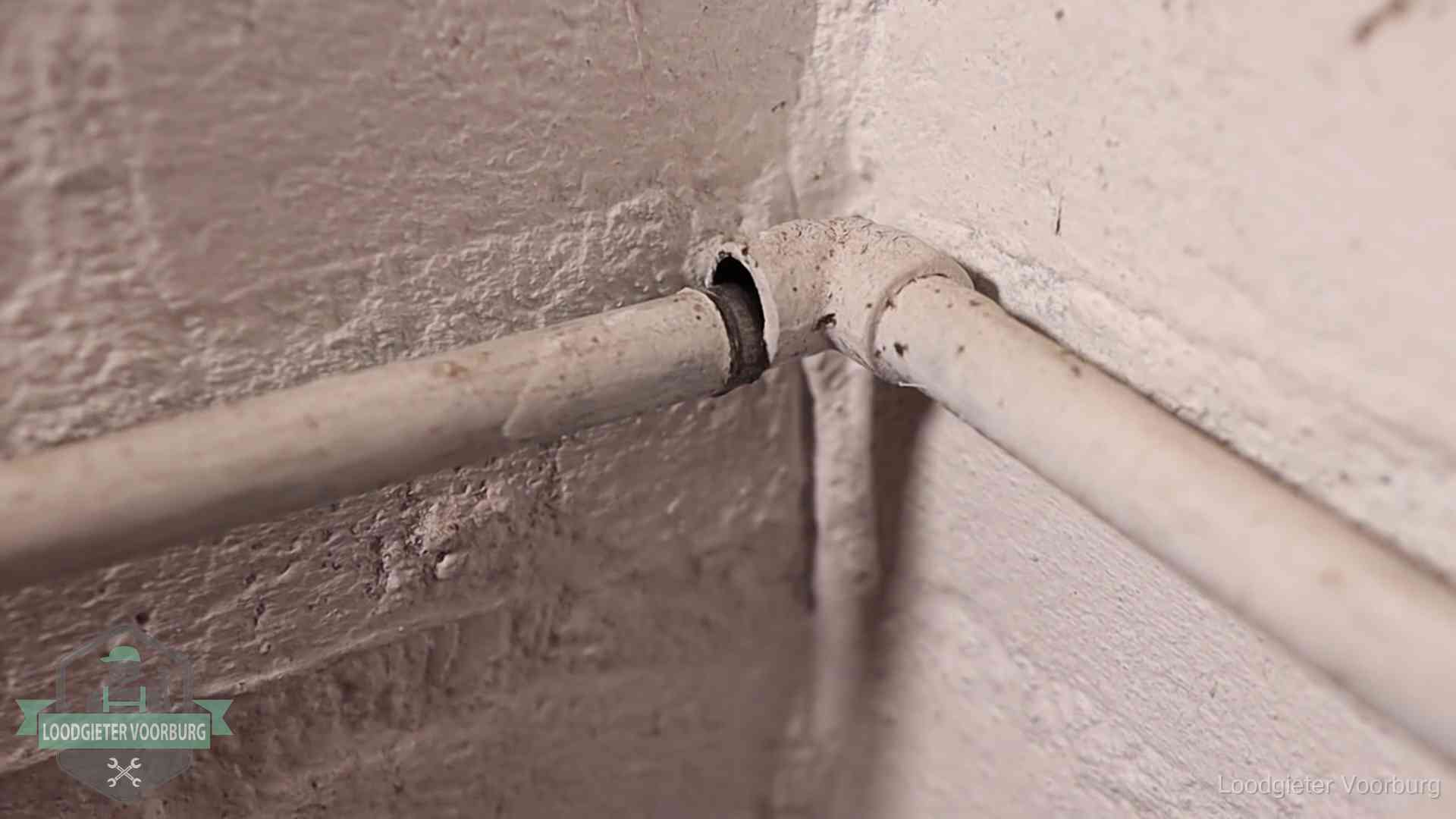 Oude geverfde waterleiding met een losliggende fitting in een woning in Voorburg