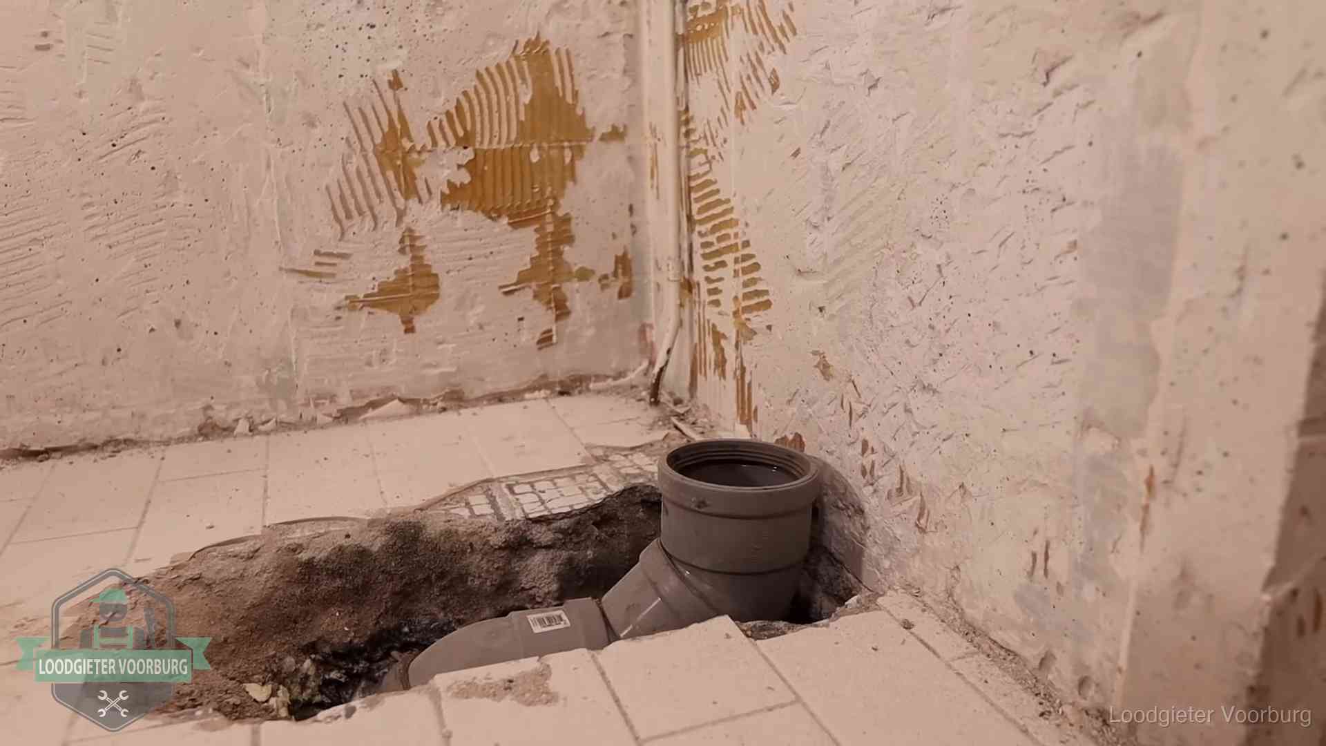 Opengebroken vloer met een nieuwe pvc-rioolbocht in een gegraven sleuf in Voorburg