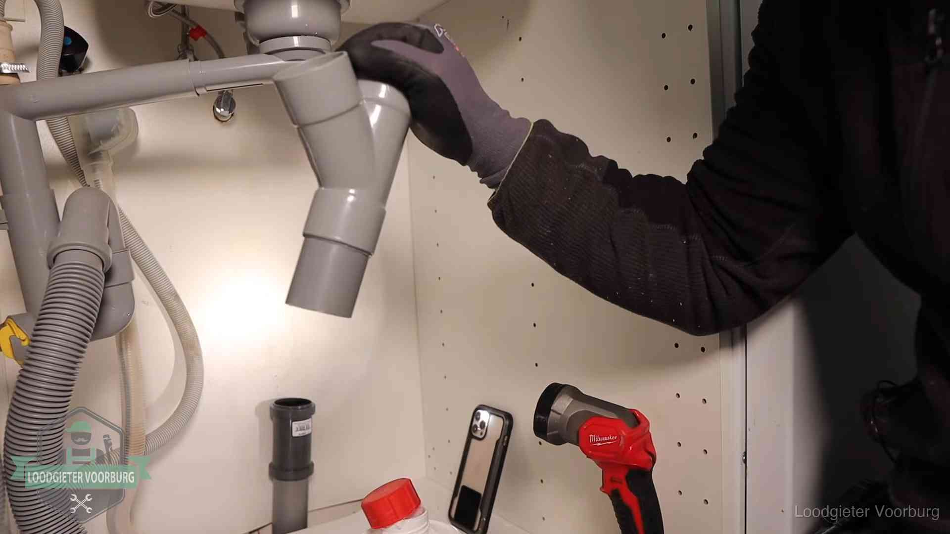 Loodgieter demonteert het sifon- en afvoerwerk onder een gootsteen in Voorburg bij stankklachten