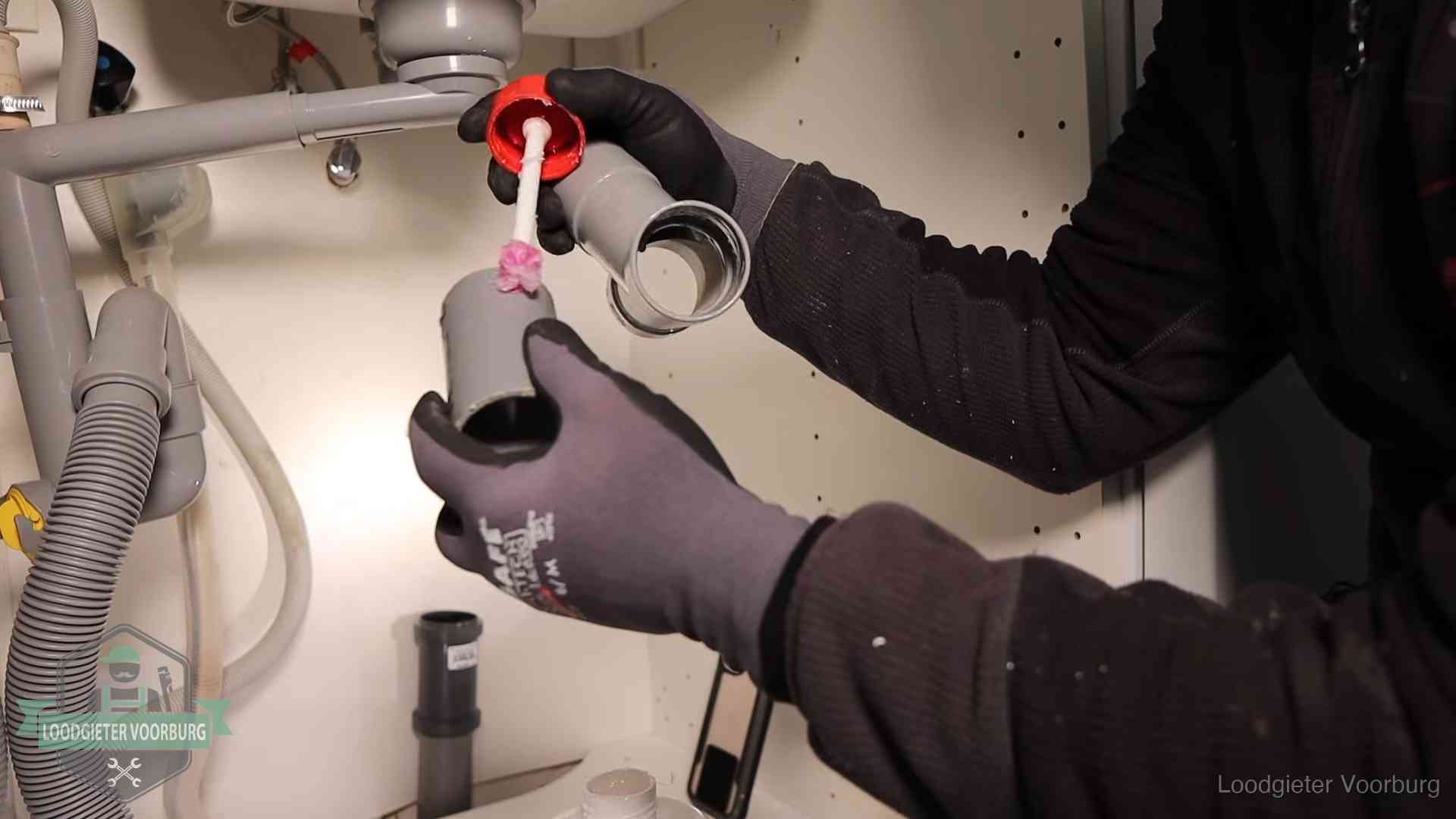 Loodgieter demonteert en reinigt de sifon onder een keukenkast in Voorburg