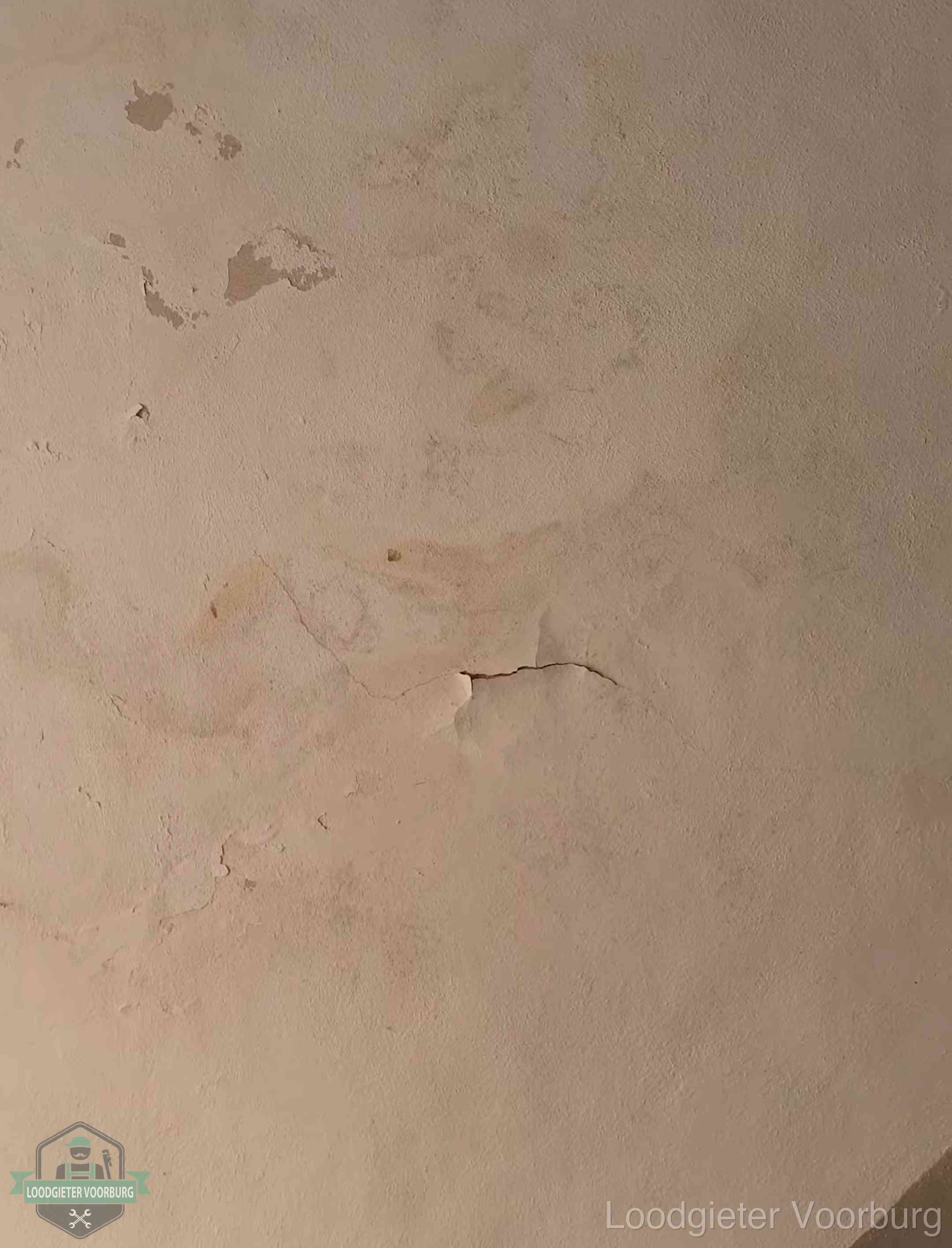 Vochtkringen en afbladderende verf op een plafond in Voorburg, schade voor het meetrapport en de verzekering
