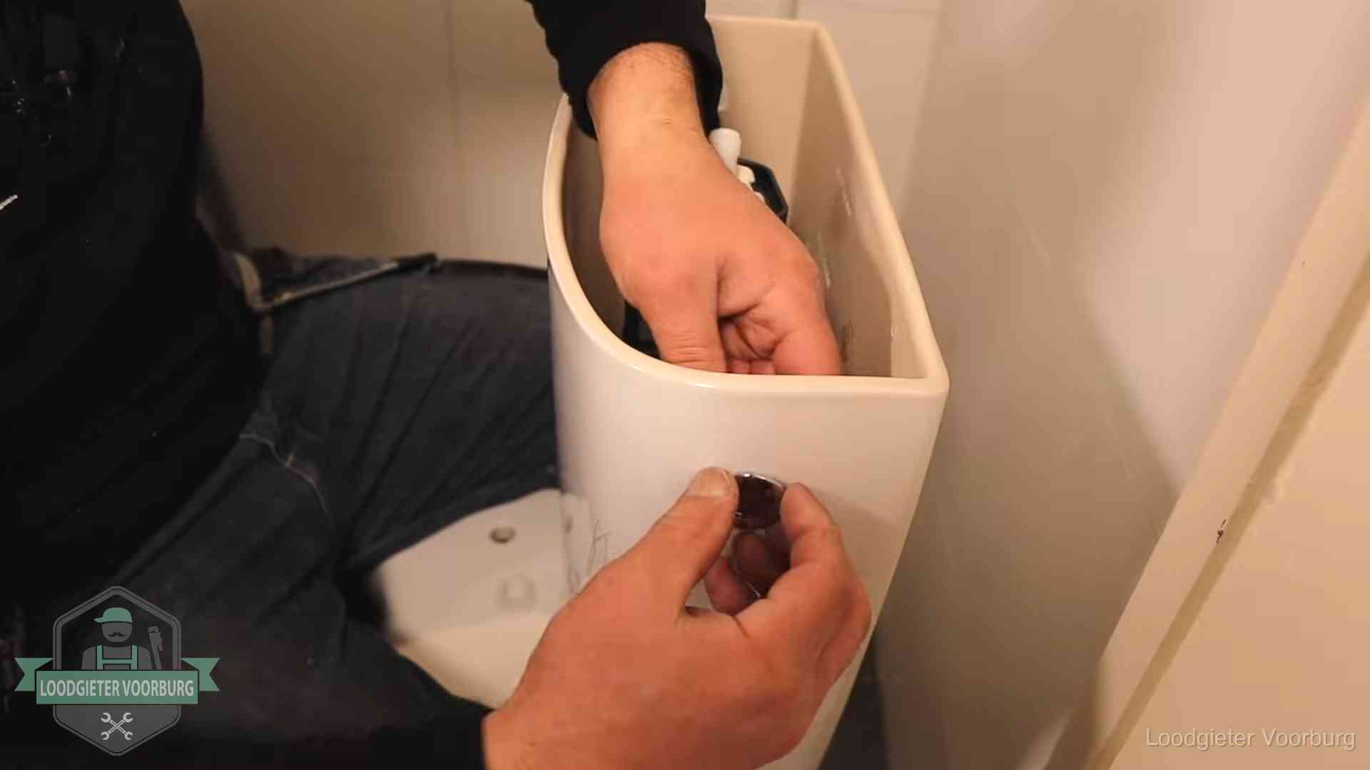 Drukknop van een duoblok-stortbak wordt gemonteerd bij een toilet in Voorburg