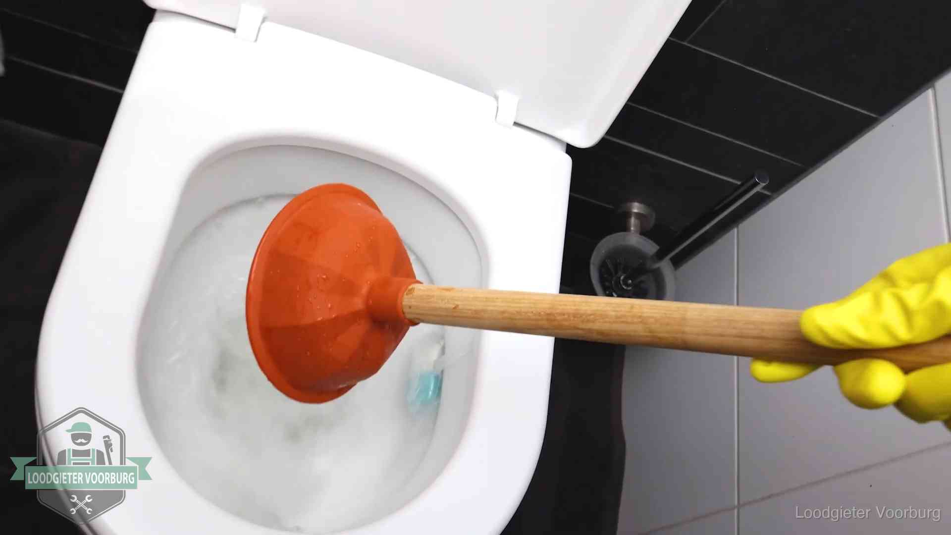 Plopper wordt in de wc-pot gedrukt bij het ontstoppen van een toilet in Voorburg